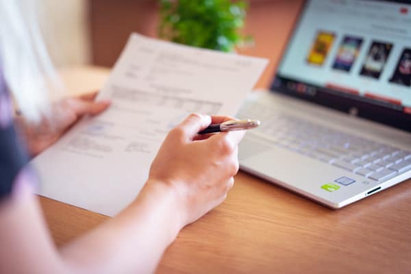 woman holding paper with laptop