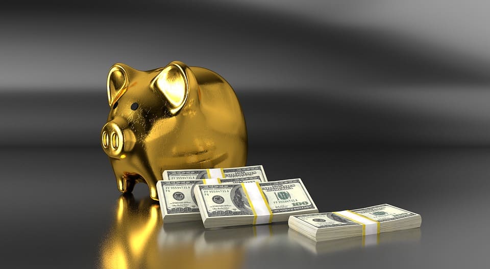 gold piggy bank with us dollar bills beside it